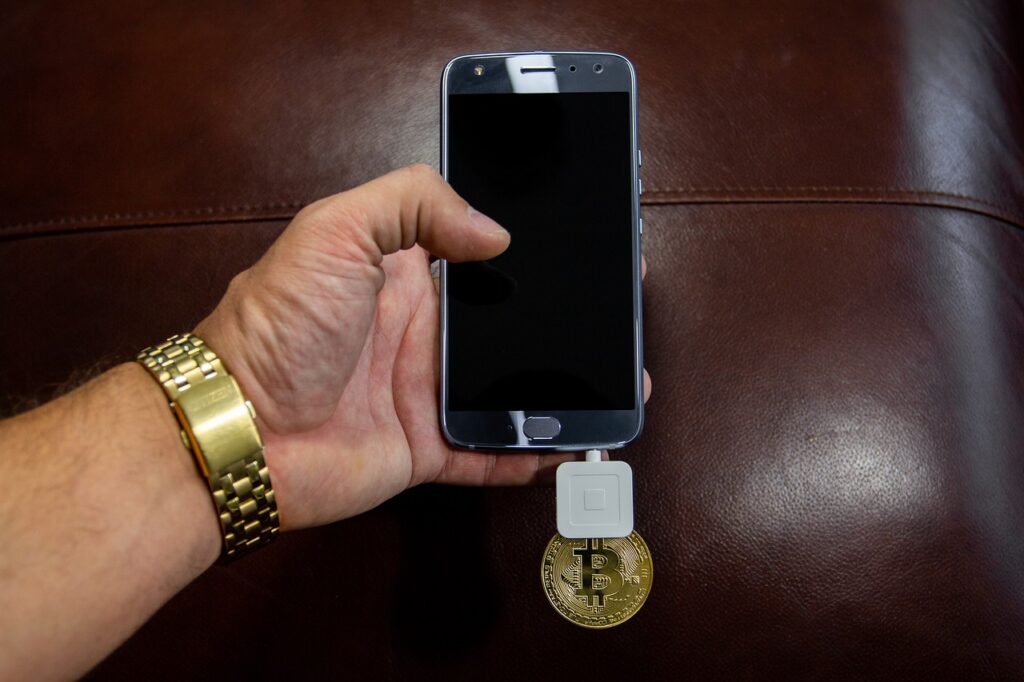 Android phone mining bitcoin with a gold bitcoin resting beneath the phone.