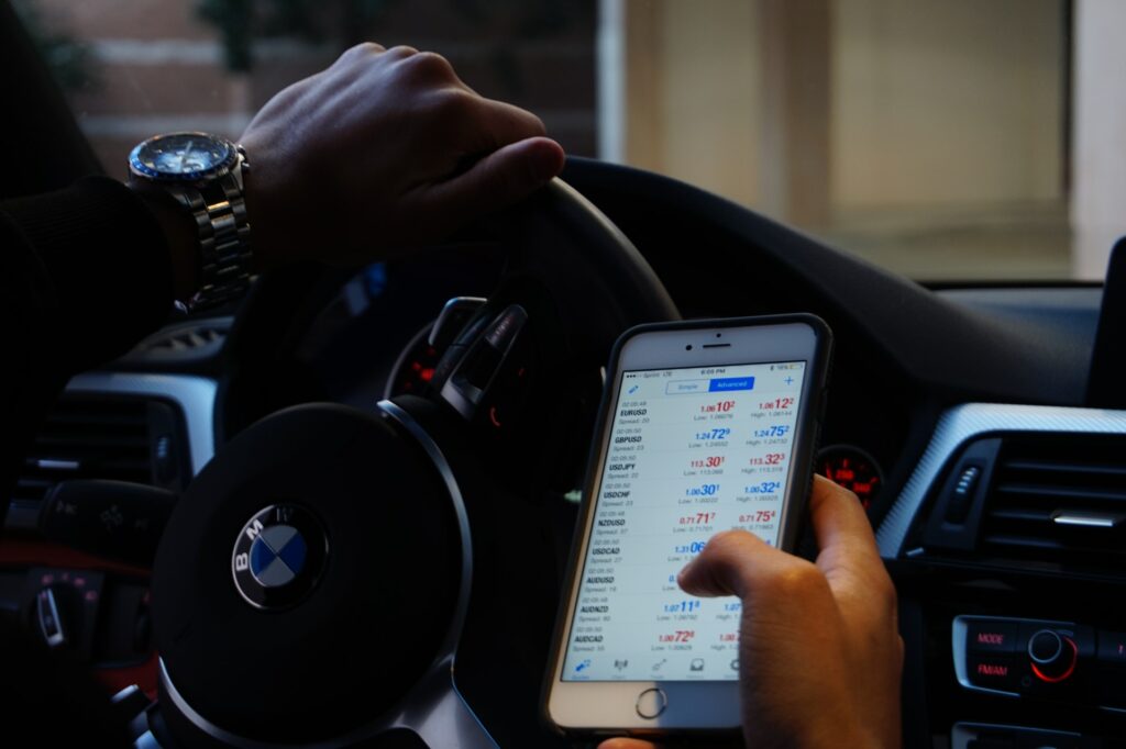 Cryptocurrency prices on an white iPhone while sitting in a BMW.