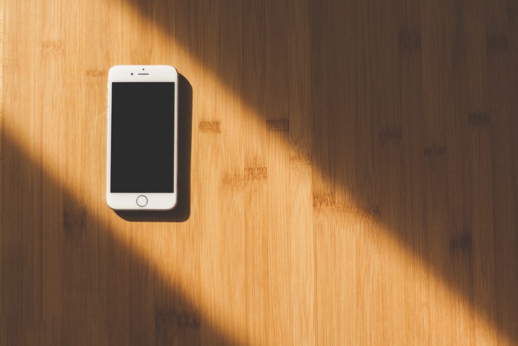 White iPhone resting on wooden table.