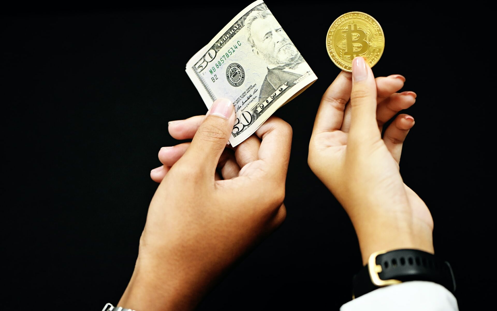 two people holding money and bitcoin in each hands.