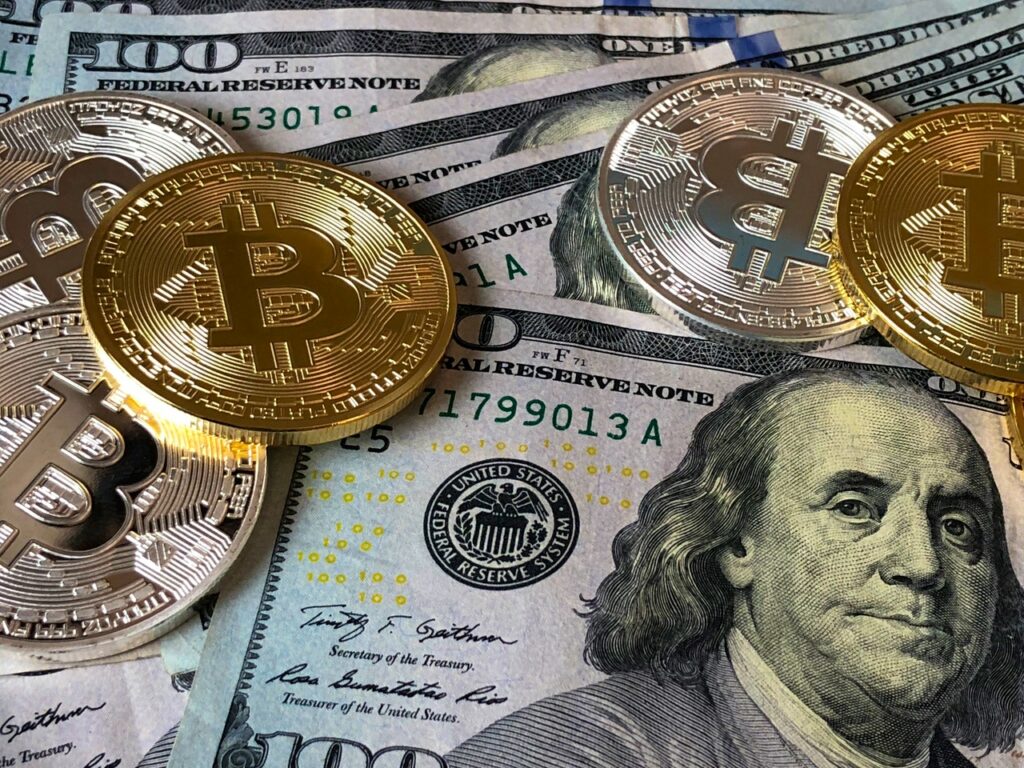 dollar bills stacked below several bitcoins