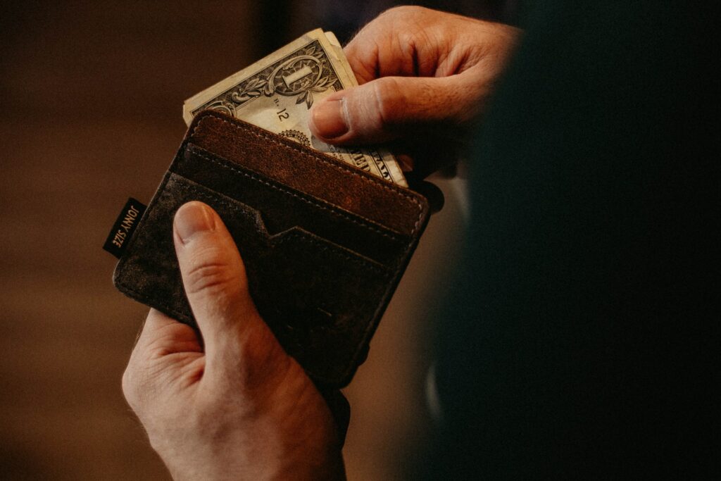 a person pulling outsome cash out of his black and brown wallet