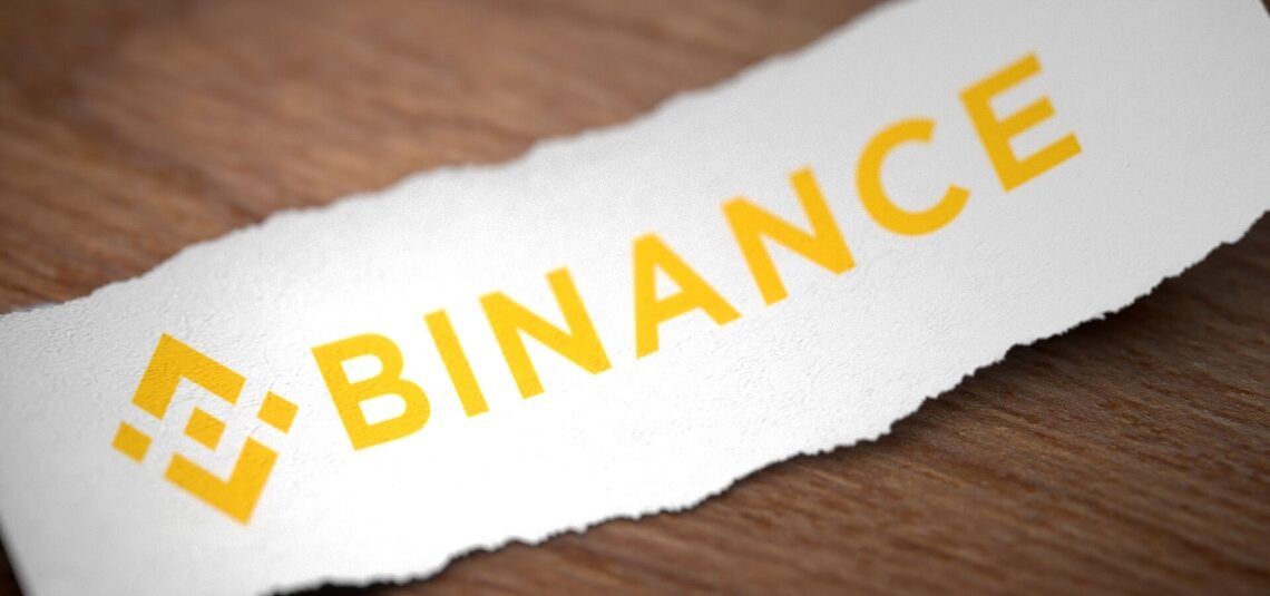 Binance written in gold characters on a white piece of paper